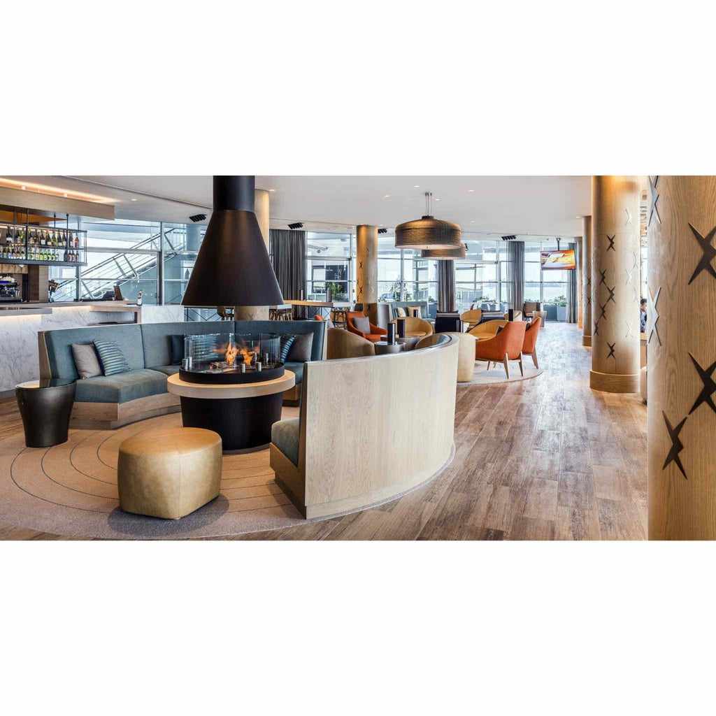 EcoSmart Fire XS340 ethanol burner with a black conical hood in a modern lounge with curved seating and wood flooring.
