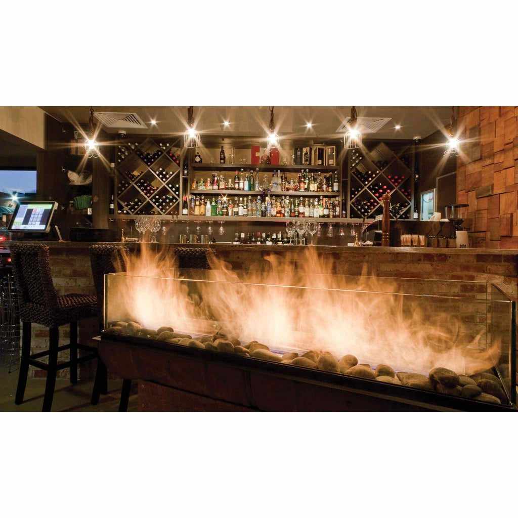 EcoSmart Fire XS340 ethanol burner with a glass screen and decorative stones, glowing with flames in a bar setting.