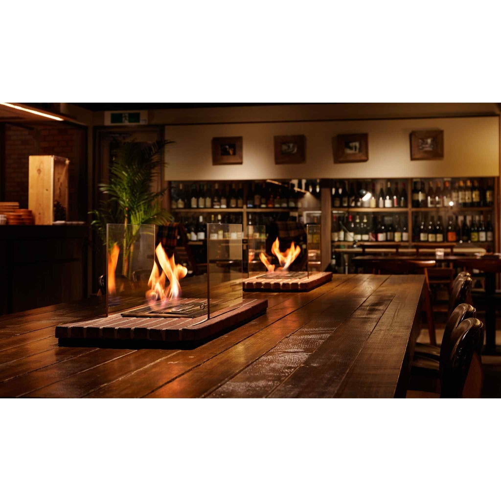 EcoSmart Fire XS340 ethanol burners with glass screens and flickering flames on a rustic wooden dining table.