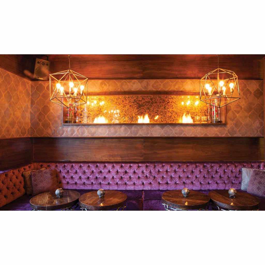 EcoSmart Fire XS340 ethanol burner integrated into a wall above a purple tufted velvet booth in a dimly lit lounge.