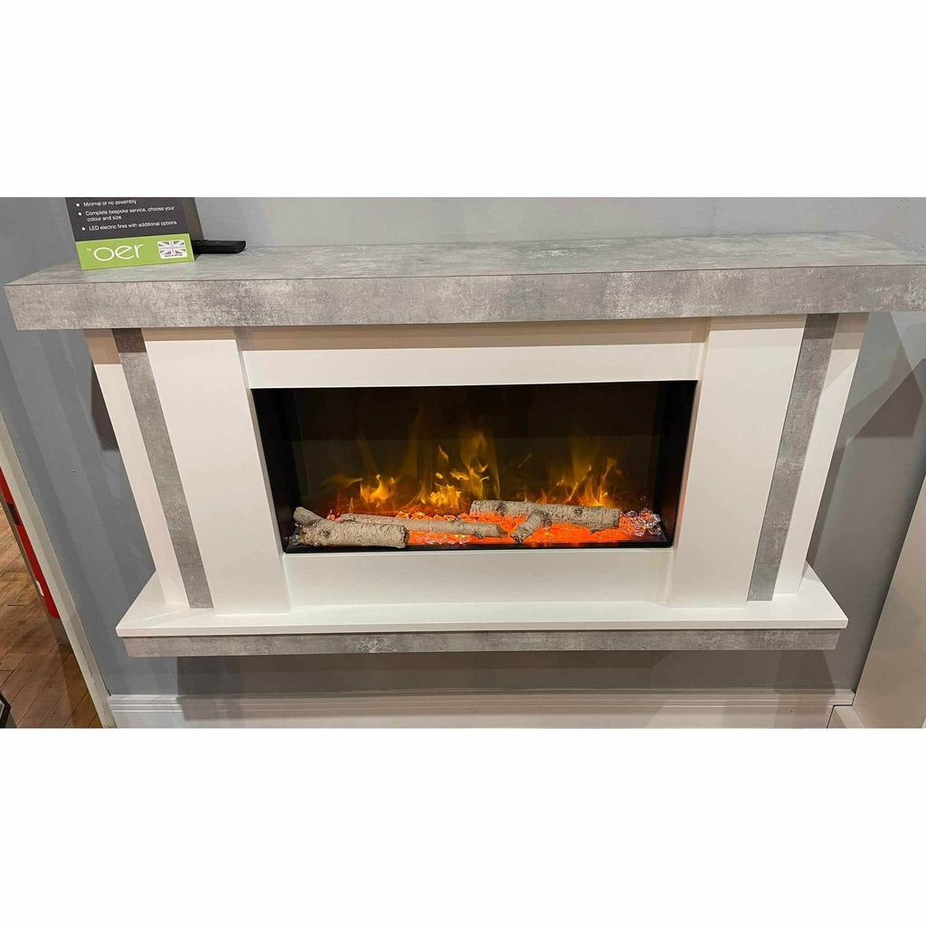 Flametek Juno electric fireplace suite with white frame, grey concrete-effect mantel, and glowing log fire effect.