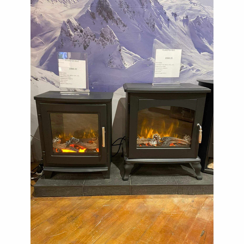 Black Flametek Reo 2kw electric stove with a glass door, glowing log flame effect, and ornate legs on a slate hearth.