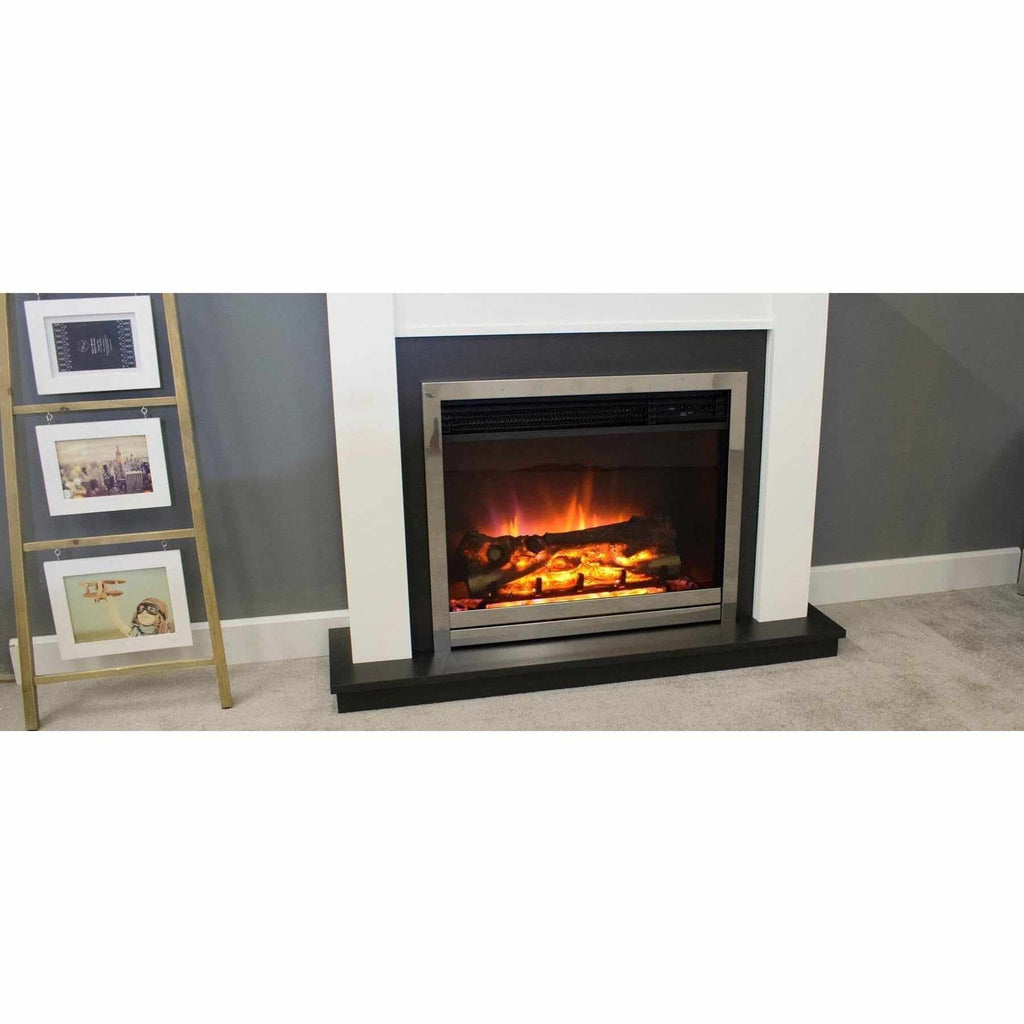 Suncrest Antigua electric fireplace suite with white surround, black hearth, and silver frame against a grey wall.