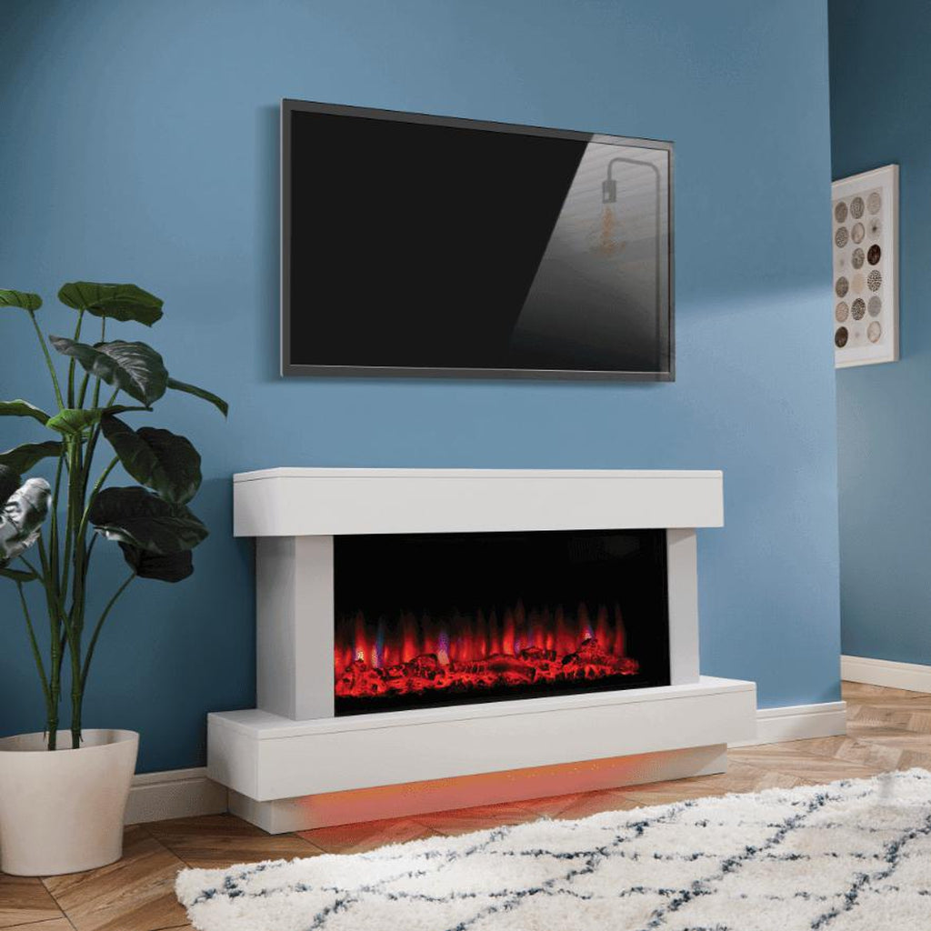 Suncrest Bourne Electric Fireplace suite in white with a glowing red flame effect against a blue wall.