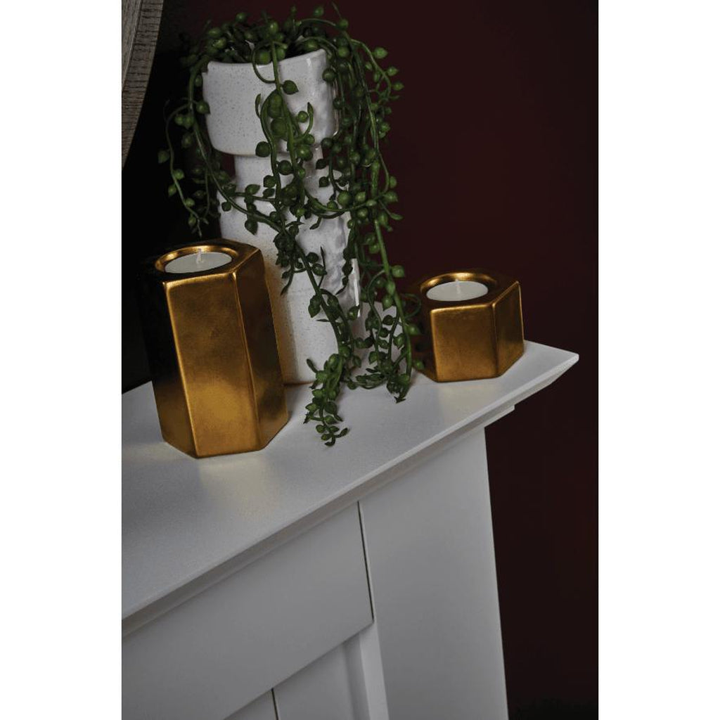 Suncrest Horley Electric Fireplace suite in white with gold hexagonal candle holders and a trailing plant.